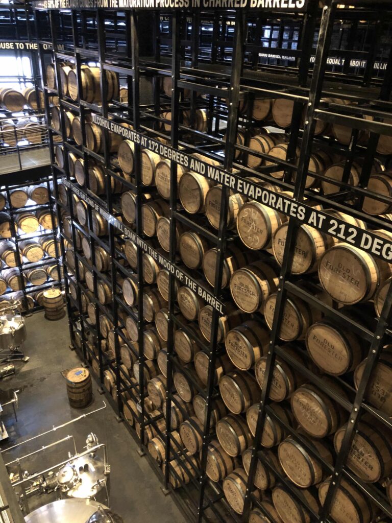 Old Forester barrels stacked toto he ceiling in an industrial warehouse.