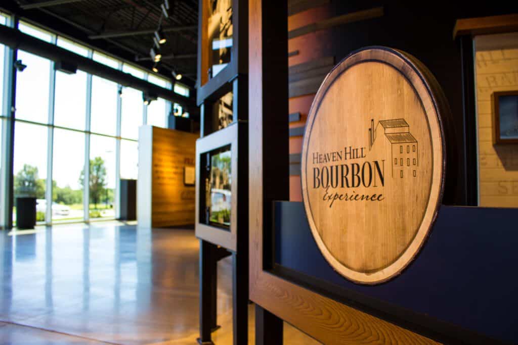 Interior of the Heaven Hill distillery on the Bourbon Trail. A hallway with floor to ceiling windows on one side and black and wood decorative panels on the other. 
