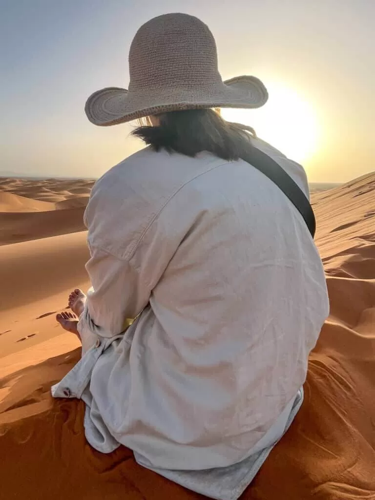 Girl looking off into the sunset in the Sahara desert in Morocco