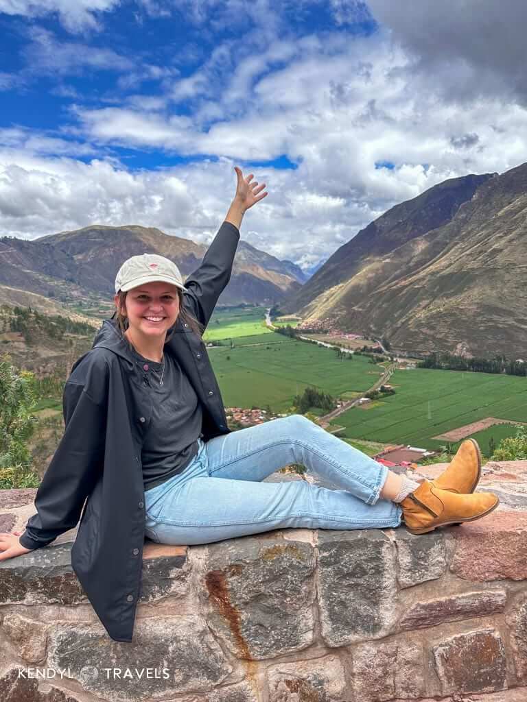 Traveler overlooking scenic view of the Sacred Valley in Peru, surrounded by mountains and farmland on a budget-friendly trip