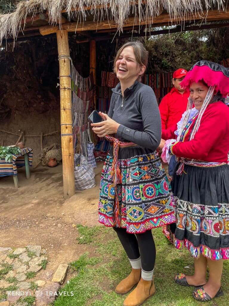 Traveler being dressed in traditional Peruvian clothing by locals in a Sacred Valley village