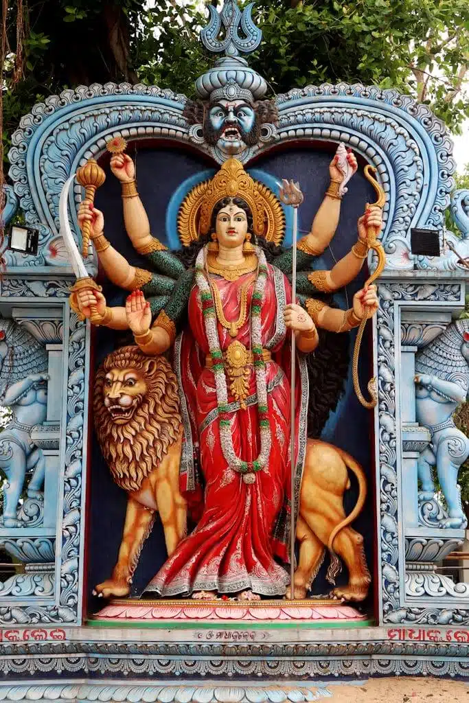 Colorful statue of a Hindu goddess with lion in Urali, India, showcasing traditional artistry.