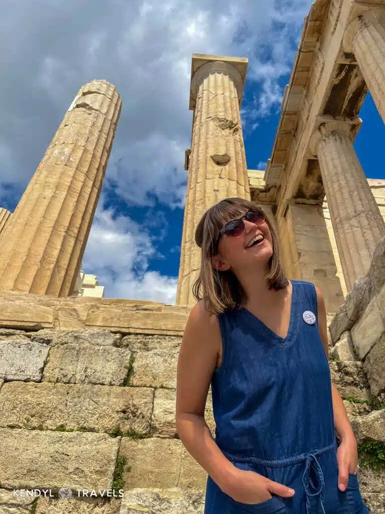 Smiling traveler in a blue dress exploring the Acropolis ruins in Athens, Greece