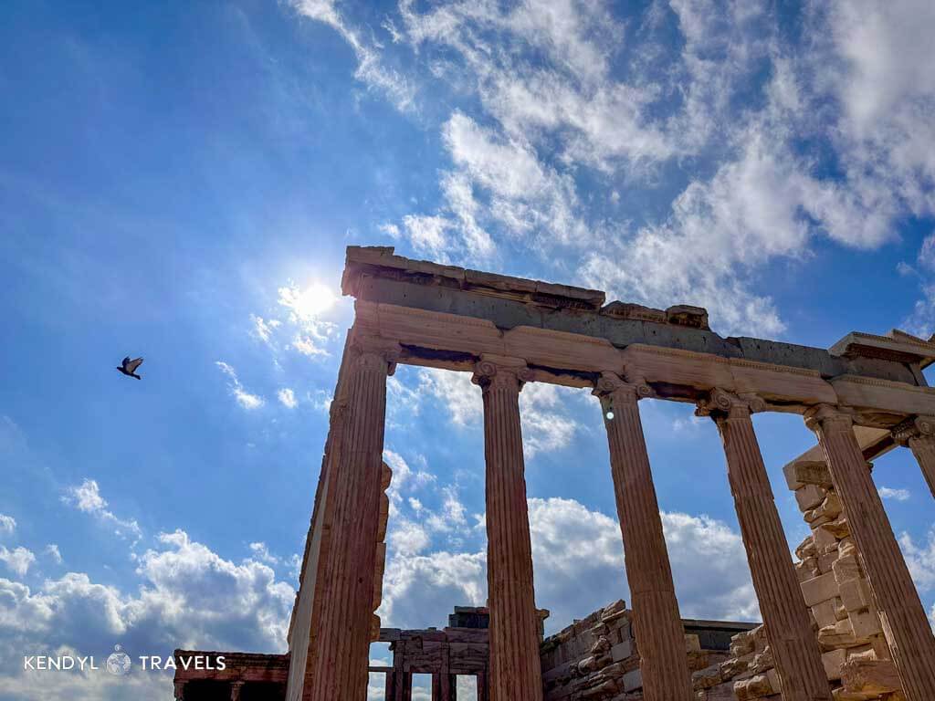 Sunlight shining through the ancient columns of the Acropolis in Athens, Greece — a must-see historic site even for budget travelers.