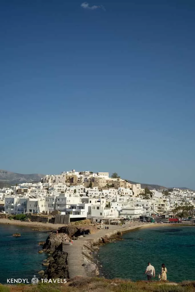 Panoramic view of Naxos Town (Chora) with its signature white buildings stacked on a hillside, seen from the causeway leading to the Portara.