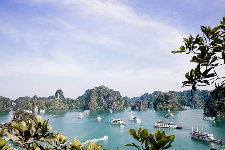 Serene Halong Bay vista featuring iconic limestone islands and boats under a clear sky.